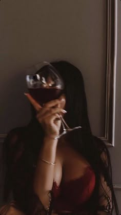 a woman holding a wine glass up to her face