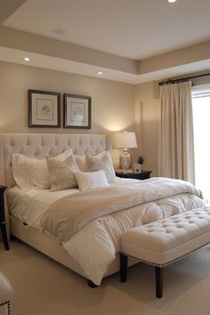 a large white bed sitting in a bedroom next to two lamps on either side of a window