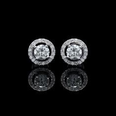 pair of diamond earrings with white gold and diamonds in the center, on black background