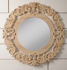 a round wooden mirror hanging on the side of a brick wall with white tiles behind it