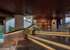 an indoor area with stairs, potted plants and pool in the background at night