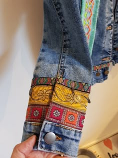 a person is holding up some jeans with different colored patches on the back of them