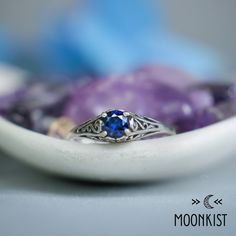 This Unique Victorian-style Sapphire Engagement Ring features a sparkling 5 mm (approximately .5 carat) round gemstone set in a dainty filigree setting.  This beautiful ring has a low-profile filigree mounting that protects the stone, but allows enough light in for it to sparkle brightly! This comfortable, snag-free setting is perfect for active people who are busy with their hands.  The mounting tapers gracefully from 6 mm at the widest point to 1.5 mm at the band. The band has been smoothed an Elegant Sapphire Moonstone Ring As Gift, Elegant Sapphire Moonstone Birthstone Ring, Celestial Sterling Silver Sapphire Promise Ring, Celestial Round Cut Promise Jewelry, 14k White Gold Jewelry With Sapphire In Round Band, Gift Moonstone Ring With Center Stone In Sterling Silver, Sapphire Moonstone Ring Fine Jewelry Gift, Solitaire Moonstone Ring For Anniversary With Round Stone, Celestial Style Rings With Center Stone In Round Cut