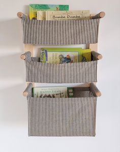 three bookshelves made out of wooden sticks and striped fabric are hanging on the wall