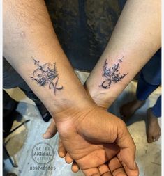 two people holding hands with tattoos on their arms