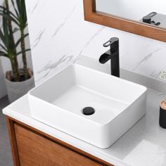 a white square sink sitting on top of a counter next to a wooden cabinet and mirror