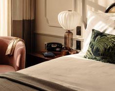 a hotel room with a bed, chair and telephone on the side table in front of it