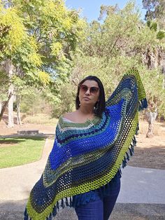 Model normally wears size US 8-Medium Wrap yourself in this multicolor crochet, acrylic and cotton poncho. This shade of green and blue poncho has the same design on both sides.  The crochet poncho wrap is the perfect accessory for layering in winter to give a classy look. This is delicately soft against your skin. The fall fringe tassels of this crochet poncho give an alluring look to your outfit.  Measurements  35" Wide X 32" Long This cotton poncho is designed to look fashionable and provide warmth. It remains breathable and comfortable rather than ward off wind and rain. Keep yourself warm and stay stylish with this poncho wrap. This gorgeous granny squares poncho is perfect for the cold months ahead.  ✔Machine wash on gentle cycle ✔Dry clean  ✔Tumble dry on low heat ✖Iron  ✖Bleach Blue Crochet Bohemian Poncho, Bohemian Blue Crochet Poncho, Blue Bohemian Crochet Poncho, Blue Crochet Shawl One Size, Multicolor Crochet Shawl For The Beach, Blue Crochet Yarn Shawl, Blue Shawl Poncho For The Beach, Blue Shawl Poncho For Beach, Blue And Green Crochet