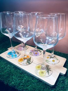 four wine glasses sitting on top of a wooden tray