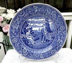 a blue and white plate sitting on top of a table next to some pink flowers