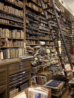 a room filled with lots of books next to a ladder