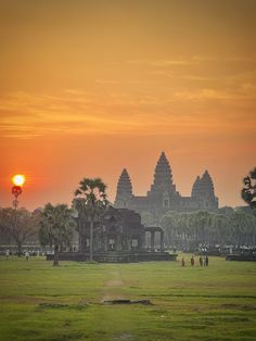 the sun is setting in front of an ancient building