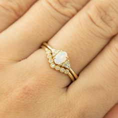 a woman's hand wearing a gold ring with an opal and diamond band