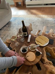 a person cutting waffles on a wooden table with wine and other food items