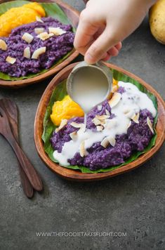 someone is dipping some kind of sauce on top of purple rice in a wooden bowl