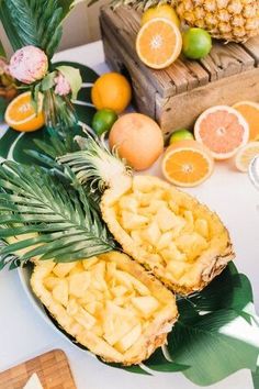 pineapples, oranges and other tropical fruits are arranged on a white table