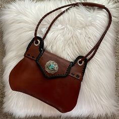 Charming Small Shoulder Bag With Adjustable 48” Long Strap. Inside Divider, Back Pocket. 117 Inches. Two-Toned: Rich Brown Leather With Black Accents. This Version Has The Silver Charm Concho And Turquoise Accent. This Is New/Never Used. Received As Gift And It’s Not My Style (But It Is Gorgeous!). Southwestern Crossbody Bag For Everyday Use, Southwestern Style Crossbody Bag For Everyday Use, Southwestern Brown Rectangular Shoulder Bag, Brown Southwestern Rectangular Shoulder Bag, Southwestern Hand Tooled Bags For Everyday Use, Brown Southwestern Style Shoulder Bag For Everyday Use, Southwestern Style Brown Rectangular Shoulder Bag, Western Bags With Concho Detail, Western Style Bags With Concho