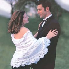 a man and woman dressed in formal wear standing next to each other on the grass