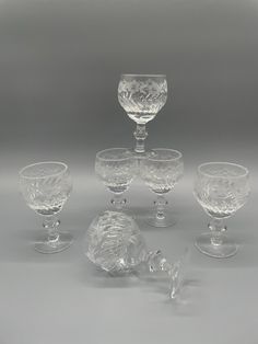 four glass goblets and two wine glasses on a gray background with one empty