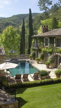 an outdoor swimming pool surrounded by lush green grass and trees, with lounge chairs around it