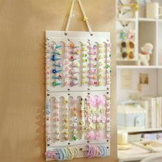 a white wall hanging with many different colored beads and bows on it's side