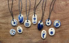 seven ceramic pendants with blue and white designs on wooden table next to each other