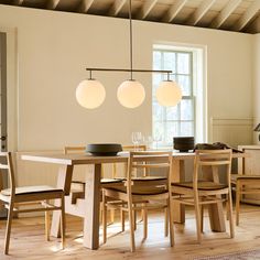 a dining room table and chairs with lights hanging from the ceiling