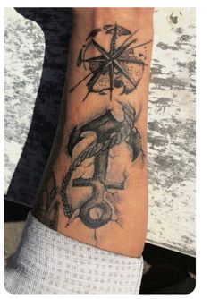 a person's arm with a compass and anchor tattoo on the left side of their wrist