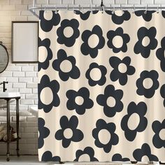 a shower curtain with black and white flowers on it in front of a brick wall