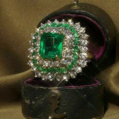 an emerald and diamond ring in a leather box