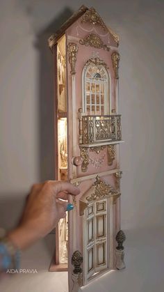 a person is painting the inside of a doll's house with gold trimmings