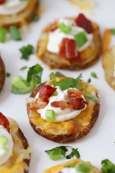 small appetizers with bacon, cheese and green onions on them are arranged on a white surface