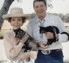 an older man and woman holding cats in their hands