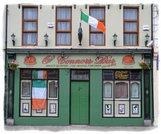 the irish flag is flying in front of a restaurant with green shutters and windows