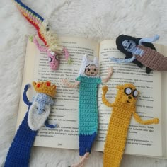 crocheted bookmarks made to look like cartoon characters on an open book