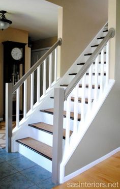 there is a clock on the wall next to the stairs in this house with tile flooring