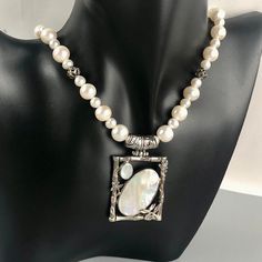 "This is a lovely, Art Nouveau style sterling silver necklace featuring a rectangular-shaped pendant with oval mother of pearl) MOP inlays and an ornate, floral overlay and stamped frame with wide, curved, ornate bale. The pendant sits (does not slide) on a beaded string of various sized freshwater pearls, with 4 openwork, ornamental sterling silver stations. The necklace has a beautifully stamped toggle clasp. On the back, the pendant is hallmarked 925 for 92.5% silver and tests positive for st Silver Sterling Silver Pearl Necklace With Polished Beads, Silver Pearl Necklace With Polished Beads In Sterling Silver, Handmade Silver Necklace With Rectangular Pendant, Elegant Jewelry With Sterling Silver Clasp And Oval Pendant, White Polished Bead Sterling Silver Necklace, White Sterling Silver Necklace With Polished Beads, White Polished Beads Sterling Silver Necklace, Handmade Silver Jewelry With Rectangular Pendant, Handmade Silver Rectangular Pendant Jewelry