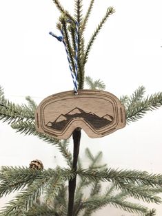 a wooden ornament with ski goggles hanging from it's side on a christmas tree