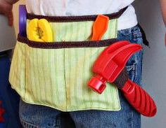 a child wearing an apron with tools in it's pocket and holding a toy wrench