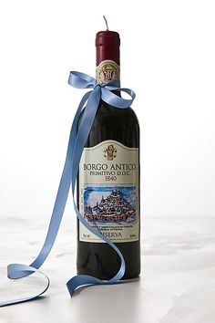 a bottle of wine with a blue ribbon on the side and a candle in the middle