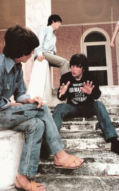 three young men sitting on steps talking and one holding his hand out to the side