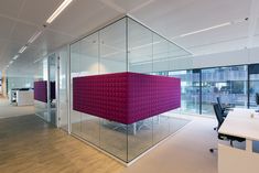 an office with glass partitions and bright colored furniture in the middle of the room