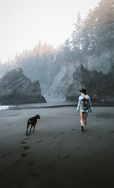 a woman walking on the beach with her dog