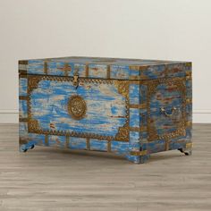 a blue chest sitting on top of a hard wood floor next to a white wall