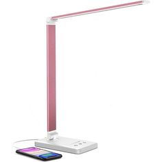 a pink desk lamp sitting on top of a table next to a cell phone and charger