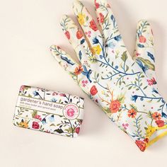 a pair of gardening gloves next to a small business card on a white table top