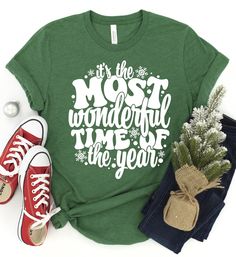 ~~It's The Most Wonderful Time Of The Year~~ Screen printed design on a soft style unisex fit tee.  Choose your shirt color and style from the menu. The design is white as shown. *2nd size chart is for a sweatshirt option. **Example shirt color is heather grass green** SHIRT DETAILS: -Heather Colors : 52% combed ringspun cotton & 48% polyester  -Solid Colors - 4.3 oz 100% preshrunk cotton  -Shoulder-to-shoulder taping -Double-needle stitched sleeves and bottom hem -Unisex sizes are similar to a Christmas Cotton T-shirt With Text Print, New Year Holiday Crew Neck T-shirt, Holiday Green Tops With Letter Print, Green Holiday Tops With Letter Print, Winter Graphic Tee With Letter Print, Winter Short Sleeve Tops With Letter Print, Short Sleeve Tops With Letter Print For Winter, Holiday Green T-shirt With Letter Print, Crew Neck T-shirt For New Year's Holiday