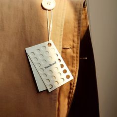 a button is attached to the back of a brown pillow with a tag on it