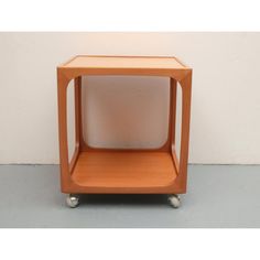 a small wooden side table with wheels on the bottom and one section missing from it