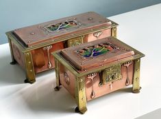 two metal boxes sitting on top of a white table next to each other with designs painted on them